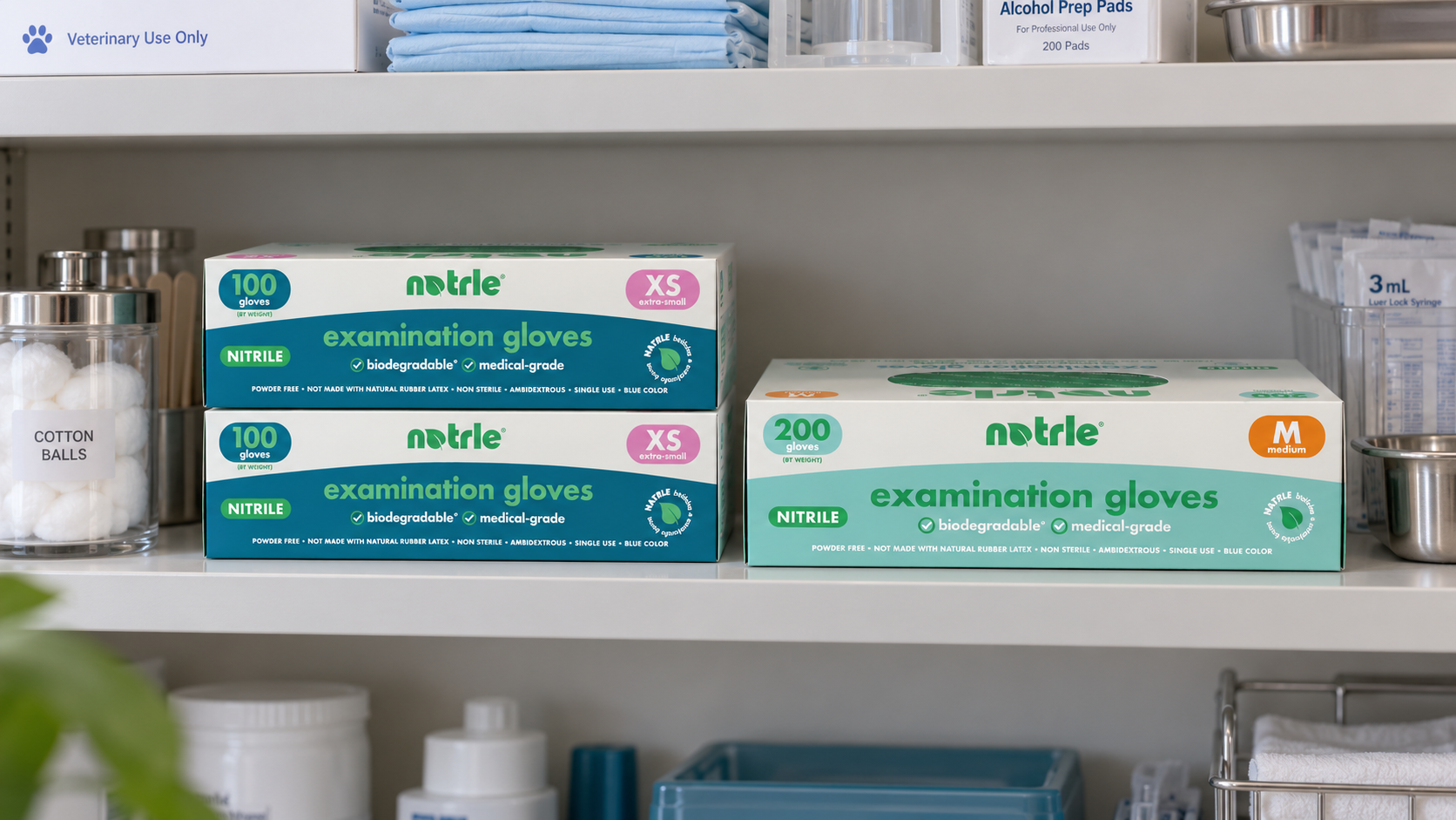 Two Natrle 100-count XS nitrile exam glove boxes stacked beside a single 200-count box on a veterinary supply shelf, showing the space saved by choosing larger boxes